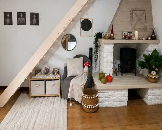Le même salon après intervention : cheminée et poutre repeintes en blanc, sol dégagé, tapis, panier et végétation installés