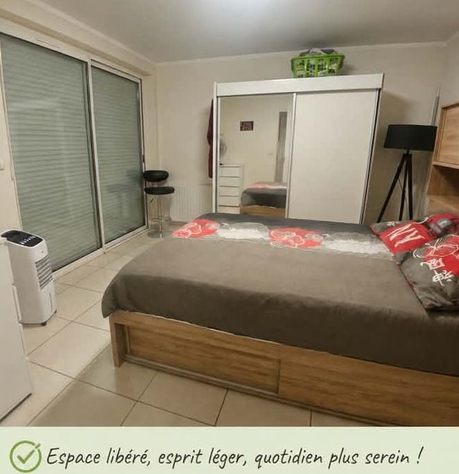 La même chambre dégagée : lit fait, sol entièrement libéré, placard fermé et rangé, luminaire sur pied