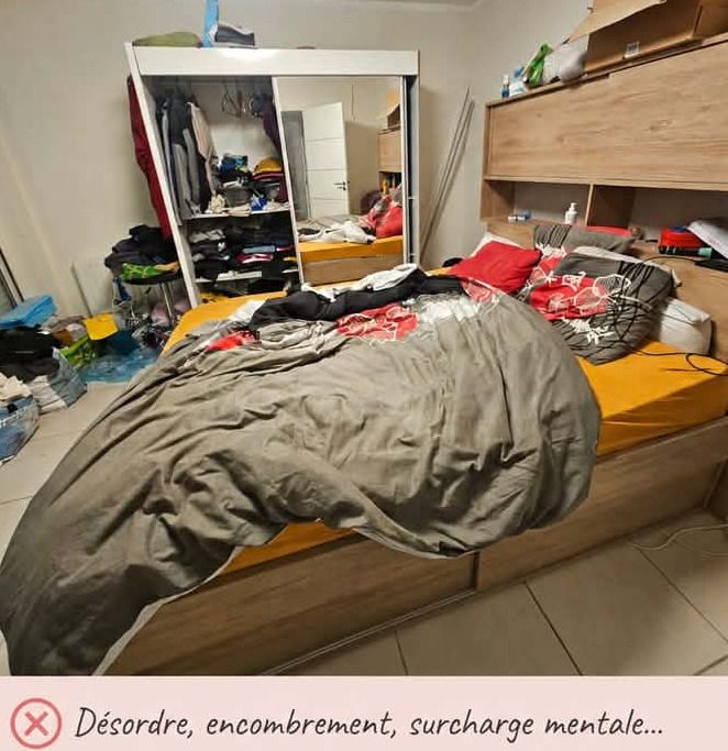 Chambre encombrée : lit défait couvert de vêtements, sacs et cartons empilés au sol, placard ouvert débordant