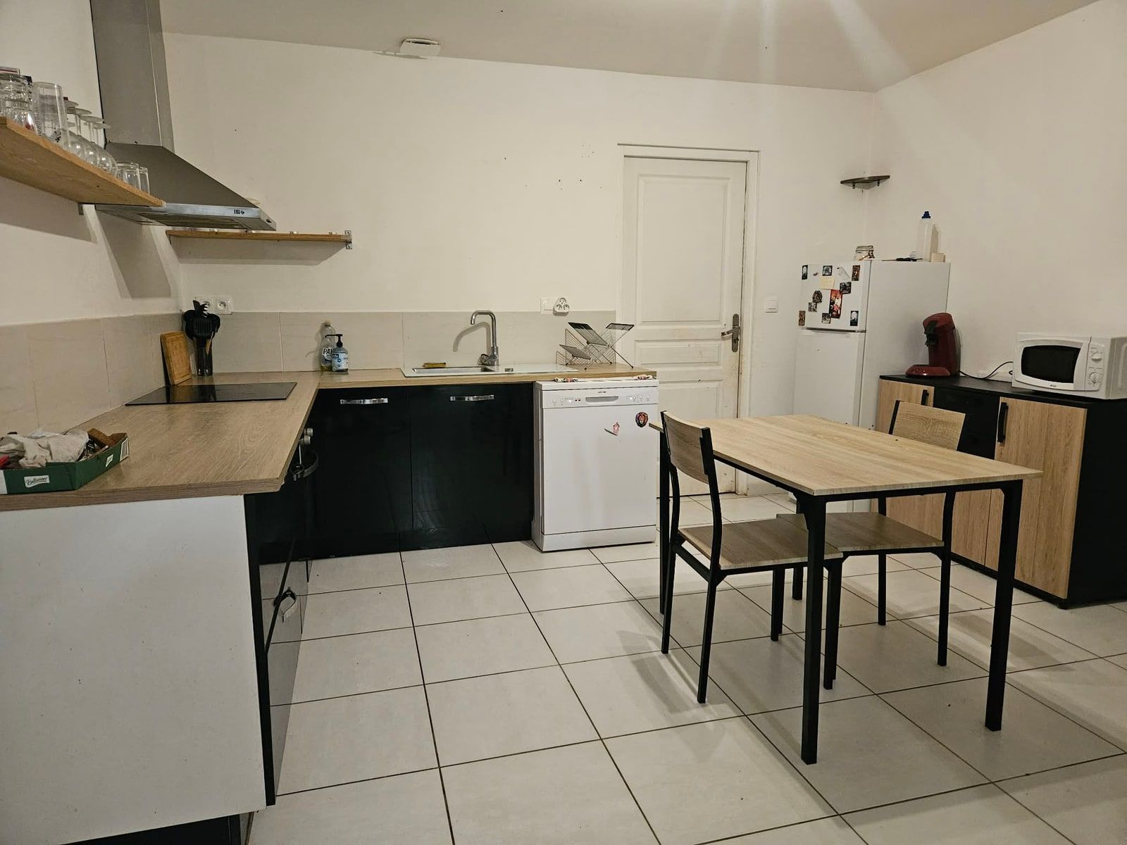 La même cuisine vue du même endroit : plans de travail entièrement dégagés, table nettoyée et vide, appareils rangés