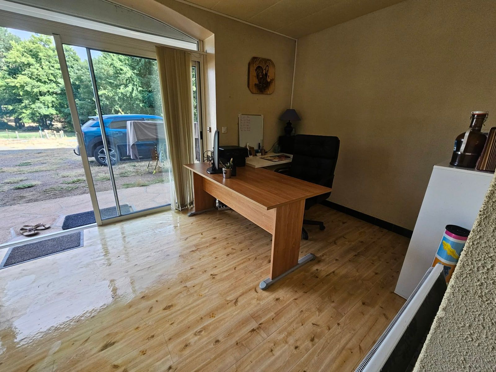 La même pièce vue du même endroit, entièrement dégagée : parquet nettoyé et libre, bureau vide, accès à la baie vitrée rétabli